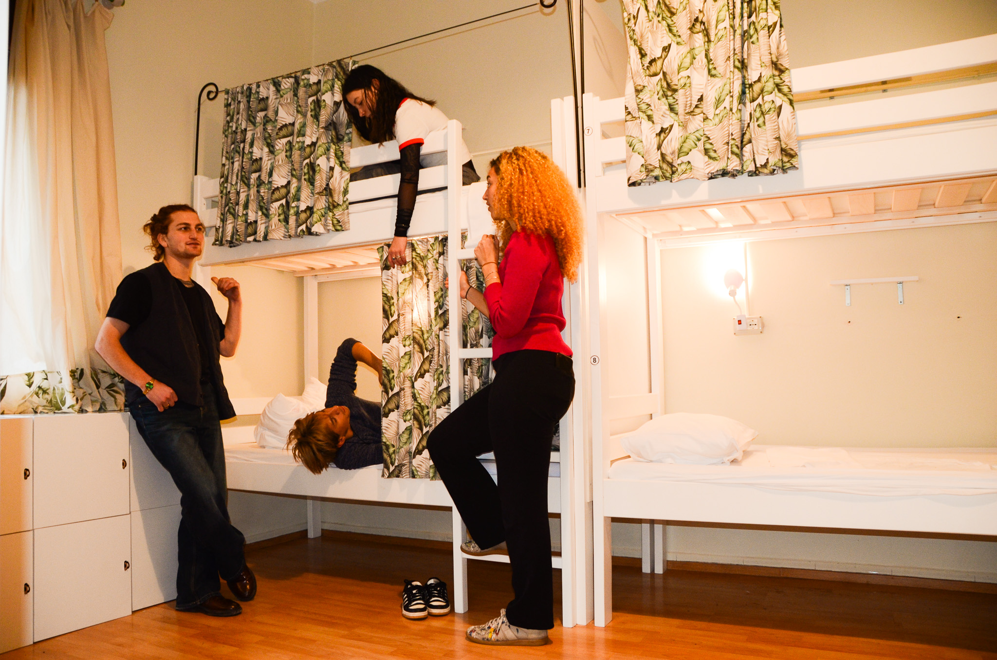 People talking and relaxing in a dorm room with bunk beds.